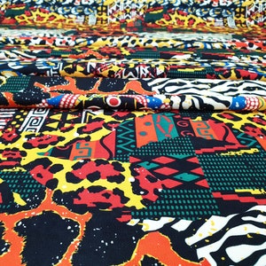 Pu&ograve; includere: Un tessuto colorato con una variet&agrave; di motivi, tra cui stampe animalier, forme geometriche e disegni tribali. Il tessuto &egrave; un mix di nero, giallo, rosso, verde e bianco.