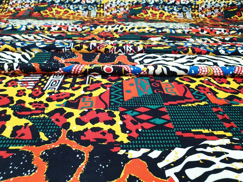 Pu&ograve; includere: Un tessuto colorato con una variet&agrave; di motivi, tra cui stampe animalier, forme geometriche e disegni tribali. Il tessuto &egrave; un mix di nero, giallo, rosso, verde e bianco.