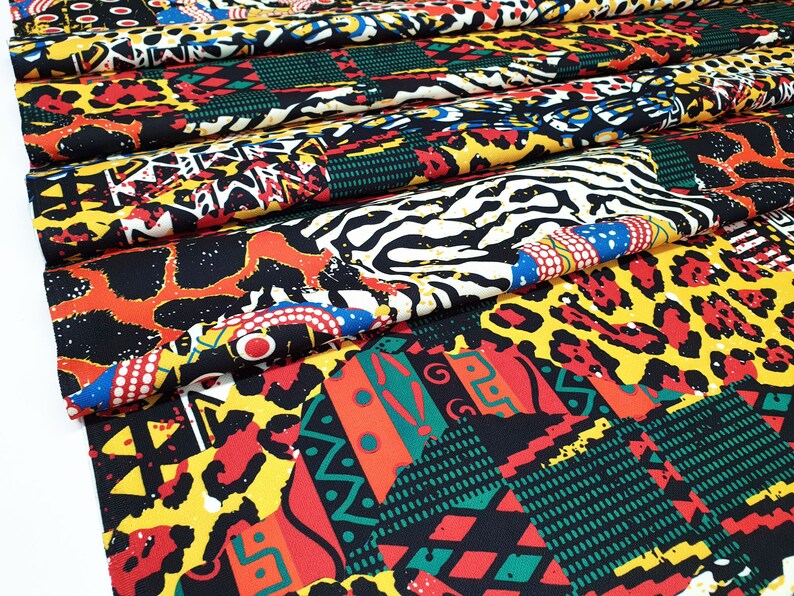 Pu&ograve; includere: Un tessuto colorato con un design a patchwork che presenta stampe animalier, motivi geometrici e forme astratte in tonalit&agrave; di rosso, giallo, nero, verde e bianco.