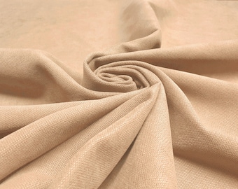 May include: A close-up of a soft, beige fabric with a textured surface. The fabric is folded and draped, creating a smooth, flowing look.