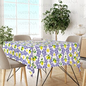 May include: White tablecloth with a lemon and blue floral pattern. The tablecloth is on a wooden table with two chairs.