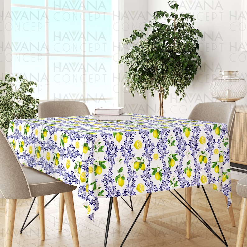 May include: White tablecloth with a lemon and blue floral pattern. The tablecloth is on a wooden table with two chairs.