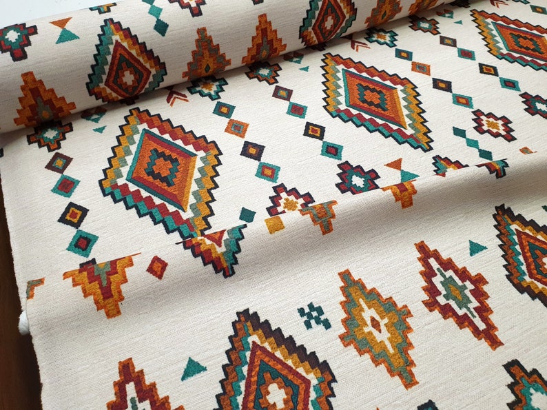 May include: White fabric with a repeating geometric pattern in shades of orange, red, teal, and brown. The pattern features diamond shapes with intricate details.