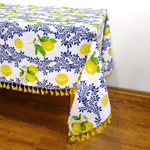 May include: White tablecloth with a lemon and blue leaf pattern. The tablecloth has yellow tassels around the edges.