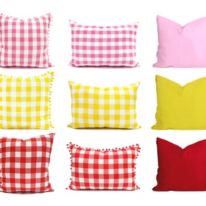 Puede incluir: Nueve almohadas decorativas en varios colores y patrones. Las almohadas están hechas de una tela suave y texturizada y presentan una variedad de patrones de cuadros. Las almohadas están dispuestas en tres filas de tres.