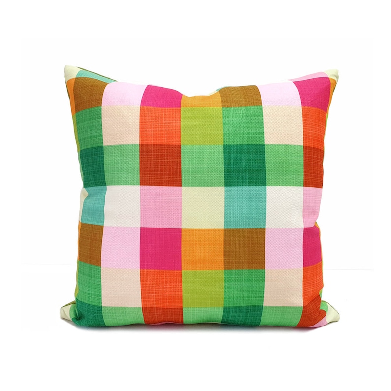 May include: A colorful pillow with a plaid pattern in shades of pink, orange, green, and brown.