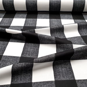 May include: Black and white buffalo check fabric with a textured weave. The fabric is folded and draped, showing the pattern.