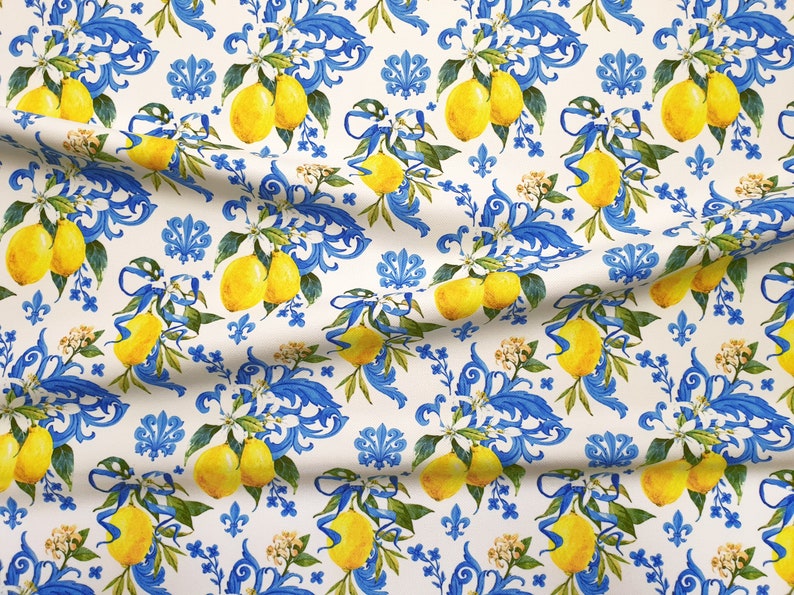 May include: A white fabric with a repeating pattern of blue and white floral designs and yellow lemons. The lemons are arranged in clusters and are surrounded by blue and white floral designs.