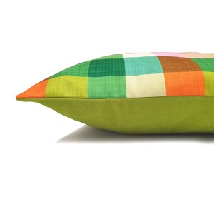 May include: A green, orange, and white plaid pillow with a solid green back.