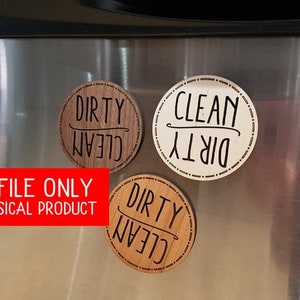 May include: Three wooden round magnets with the words "Dirty Clean" written on them. The magnets are attached to a stainless steel refrigerator.