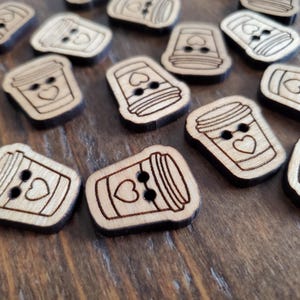 May include: A collection of wooden buttons shaped like coffee cups with hearts on them. The buttons are brown and have a natural wood finish.