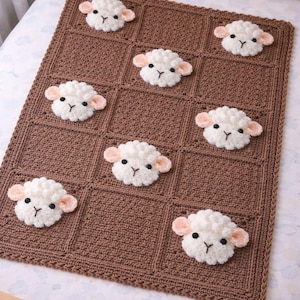 May include: A brown crocheted blanket featuring a grid pattern with seven white sheep appliques. Each sheep has a textured white wool body, light pink ears, and black embroidered eyes and nose. The blanket has a solid brown crocheted border.