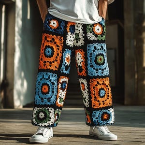 May include: Vibrant crochet trousers with a black base, showcasing square patterns in orange, blue, white, and green. The person is wearing white trainers and a white t-shirt.