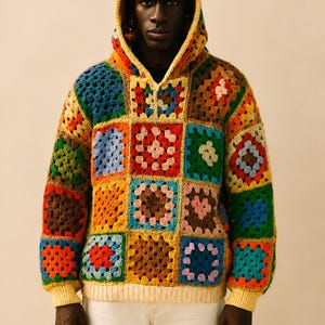 May include: A vibrant, patchwork crochet hoodie with a hood and long sleeves. The sweater features a variety of square patterns in shades of blue, orange, green, and yellow. The cuffs and bottom hem are a solid yellow colour.