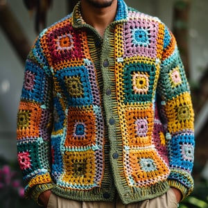 Könnte beinhalten: Eine bunte gehäkelte Strickjacke mit Patchwork-Muster, das aus Quadraten in Blautönen, Grün, Gelb, Orange, Rot und Lila besteht. Die Strickjacke hat einen Knopfleistenverschluss und lange Ärmel.