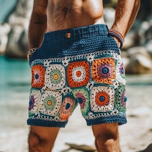 Puede incluir: Pantalones cortos de ganchillo con cintura azul oscuro y un patrón de cuadrados de la abuela multicolor. Los cuadrados están compuestos por hilo blanco, naranja, verde, morado y amarillo, creando un diseño geométrico texturizado.