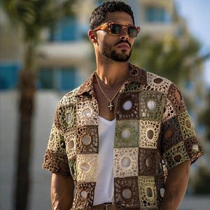 May include: A short-sleeved, open-collar crochet shirt in shades of brown, green, and beige. The shirt features a square pattern with open circles in the center of each square. The shirt is worn over a white undershirt.
