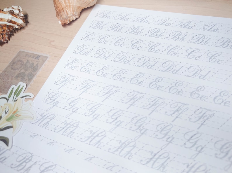 May include: A white sheet of paper with cursive letters of the alphabet written in grey ink. The letters are written in rows, with each row containing a different letter. The letters are spaced evenly apart and are written in a neat and legible style.