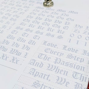 May include: A white sheet of paper with a grid pattern and gray lettering. The letters are in a gothic font and include the alphabet, numbers, and the phrase "Love is Every Step".