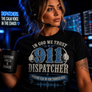 Könnte beinhalten: Schwarzes T-Shirt mit einem blau-weißen Aufdruck mit der Aufschrift "911 DISPATCHER" mit dem Text "IN GOD WE TRUST" darüber und "EVERYONE ELSE WE RUN THROUGH NCIC" darunter. Eine schwarze Tasse mit "CAFFEINE CALLS & CHAOS" wird in der Hand gehalten.