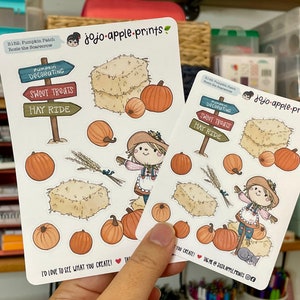 Op de afbeelding: Twee witte stickervellen met jojo-apple-prints branding, een vogelverschrikker, hooibalen, pompoenen, korenaren en wegwijzers met de tekst Pumpkin Decorating, Sweet Treats en Hay Ride. De tekst luidt I'd love to see what you create!