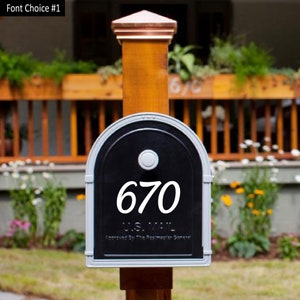 May include: A black mailbox with a white number "670" on the front. The mailbox is mounted on a wooden post with a copper top.