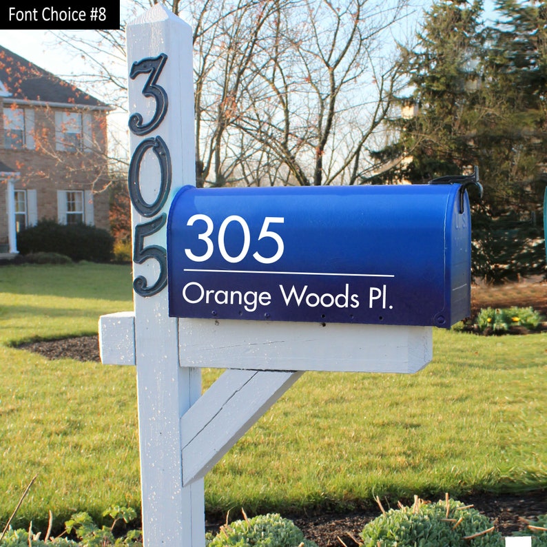 Blue mailbox on a white pole with a number 305 displayed vertically on the pole and a white decal that displays 305 Orange Woods Pl.