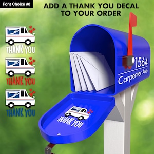 Blue mailbox sitting on a white pole. The mailbox has a white decal that nicely displays their address, number over street name separated by a horizontal line. On the mailbox lid, there is a decal of a mail truck with the word thank you under it.