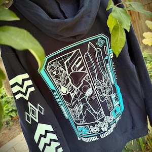 May include: A black hooded sweatshirt featuring a large cyan and white graphic on the back depicting a robotic bear warrior holding a sword. The text ANIMAL WARRIOR is printed at the bottom. The sleeve has a series of light green geometric symbols.