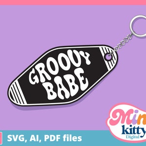 Op de afbeelding: Een zwart-wit motel sleutelhanger met de tekst "Groovy Babe" in een retro lettertype. De sleutelhanger is bevestigd aan een zilveren sleutelring.