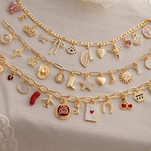 May include: Three gold-tone chain charm bracelets featuring various pendants including a butterfly, crown, bow, paw print, fan, strawberry, angel, letter R, ladybug, cowboy hat, boot, star, heart, sun, airplane, key, playing card, and the text Be Free.