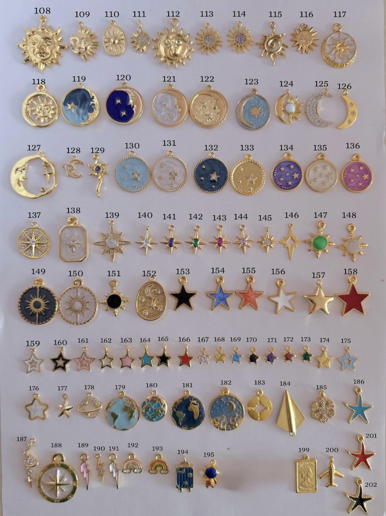 Puede incluir: Una colecci&oacute;n de colgantes dorados con diversos dise&ntilde;os celestiales y de viaje. Los colgantes incluyen soles, lunas, estrellas, planetas y otros elementos decorativos. Los colgantes est&aacute;n dispuestos sobre una superficie blanca.