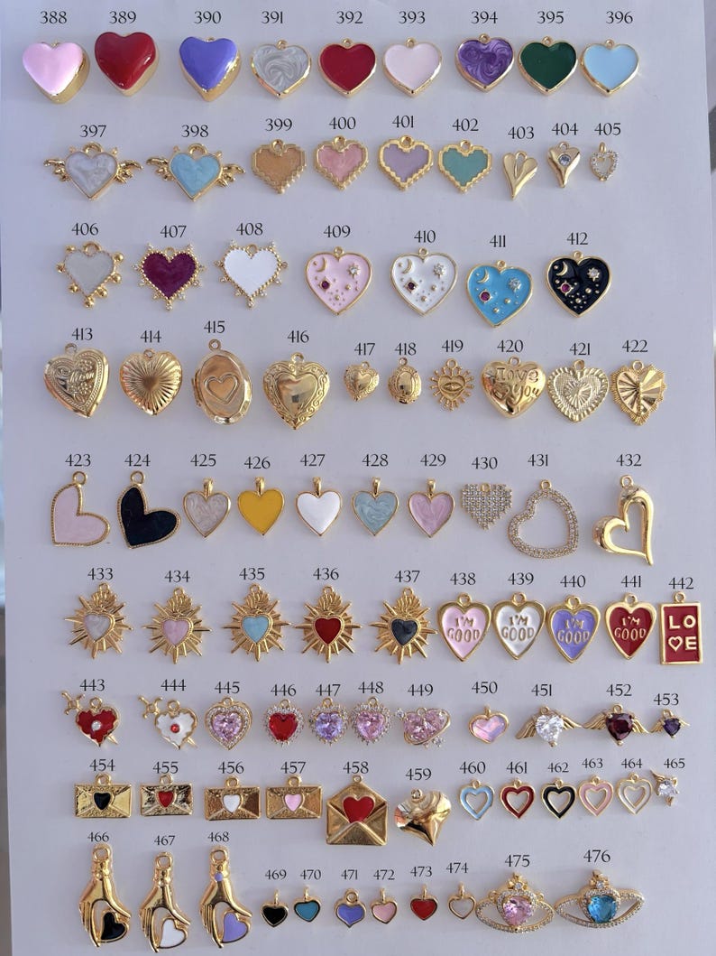 Puede incluir: Una colecci&oacute;n de colgantes y abalorios en forma de coraz&oacute;n en varios colores y dise&ntilde;os. Los colgantes incluyen acabados dorados, plateados y esmaltados, algunos con texto y adornos. La imagen muestra una variedad de estilos.