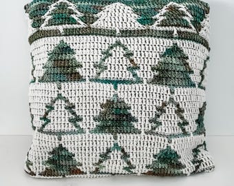 May include: A white crocheted cushion with a green and brown geometric pattern of pine trees.