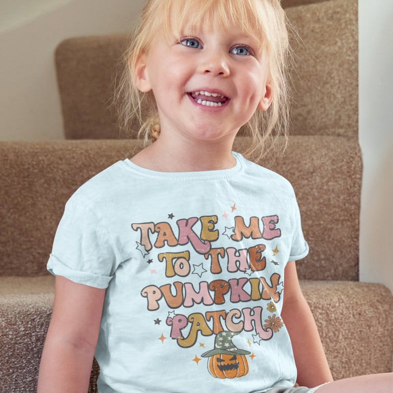 May include: A light blue t-shirt with a retro-style graphic that says "Take Me To The Pumpkin Patch" with a pumpkin wearing a witch's hat.