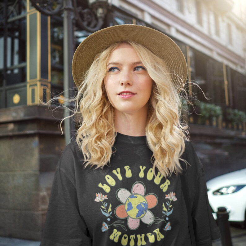 May include: A black t-shirt with a retro-style graphic that says "Love Your Mother" with a flower and a globe in the center.