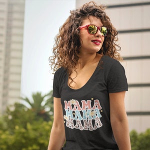 Puede incluir: Una camiseta negra de cuello redondo con el texto "Mama Mama Mama" en rosa, azul y blanco con detalles florales y de estampado de leopardo.