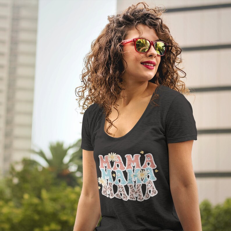 Puede incluir: Una camiseta negra de cuello redondo con el texto "Mama Mama Mama" en rosa, azul y blanco con detalles florales y de estampado de leopardo.
