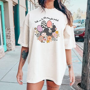 May include: A white oversized t-shirt with a paw print design featuring pumpkins, flowers, and the text "take me to the pumpkin patch".