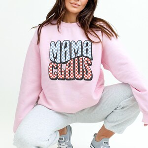 May include: Pink sweatshirt with a red and blue chequered graphic that says "Mama Claus".
