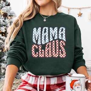 May include: Green sweatshirt with a checkered design that says "Mama Claus" in blue and red.