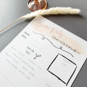 Op de afbeelding: Een printbare bruidsmeisjes-vragenlijst met een roze aquarel achtergrond. De vragenlijst vraagt naar de naam en rol van elke bruidsmeisje en bevat een "Dit of Dat" sectie met vragen zoals "Zout/Zoet" en "Koffie/Thee". Het vraagt ook naar een favoriete lied.