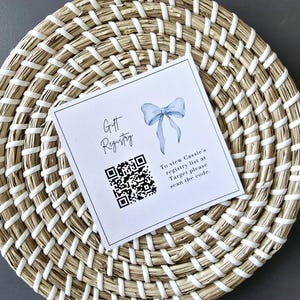 May include: A white card with the text "Gift Registry" and a blue bow. A QR code is printed on the card with the text "To view Cassie's registry list at Target please scan the code."