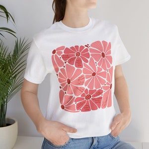 May include: White t-shirt featuring a floral design in shades of pink and red. The flowers contain text such as "Fuck Trump" and "Fuck everyone". The shirt is a casual, everyday wear item.