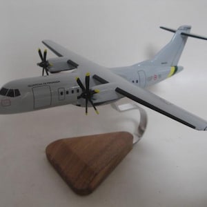 May include: A model airplane, painted in shades of gray, with black propellers and wing accents. The model is mounted on a silver stand with a wooden base. The text "GUARDIA DI FINANZA" is printed on the side of the plane.