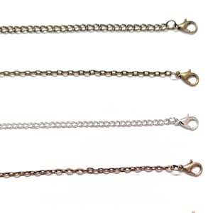 May include: Five different chain styles with lobster clasps. The chains are silver, gold, rose gold, and two shades of bronze.