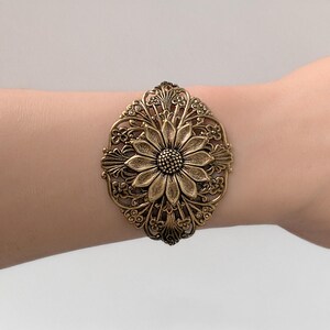 Vintage brass sunflower bracelet with leaf detail displayed on wrist.