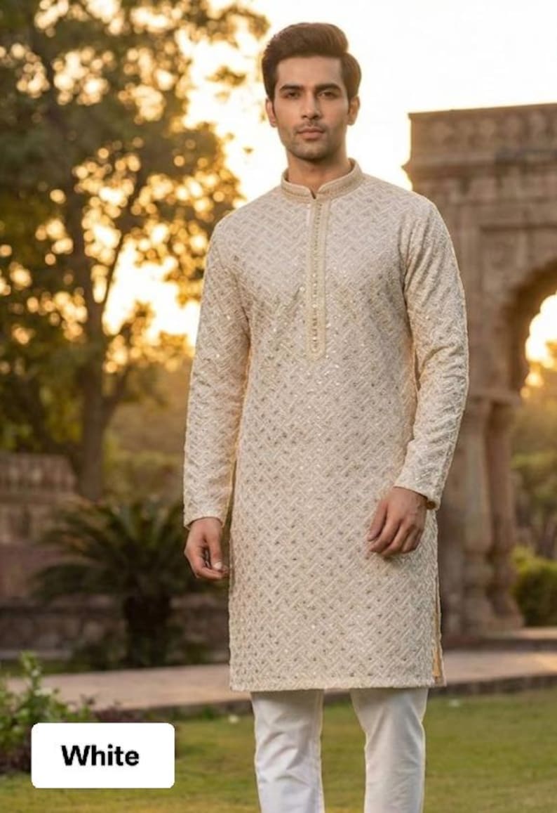 May include: Cream-colored kurta with intricate embroidery and a mandarin collar. The long-sleeved tunic is paired with white pants. The image has the word "White" in a white box at the bottom.
