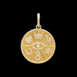 May include: Gold pendant necklace with a round charm featuring a diamond-encrusted eye, heart, crown, star, and horseshoe. The charm is surrounded by a circle of smaller diamonds.