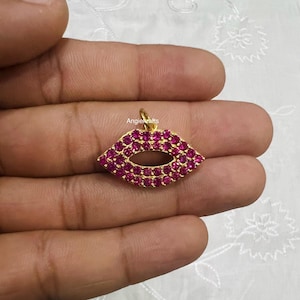 May include: Gold-tone pendant charm shaped like a pair of lips, encrusted with pink rhinestones. AngieKrafts is printed on the pendant.